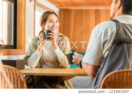Couple, man and woman (talking, conversation) drinking coffee while using a computer at home, villa, cottage 121991697