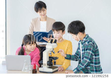 Elementary school students observing through a microscope 121992258