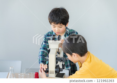 Elementary school students observing through a microscope Elementary school students observing through a microscope 121992263