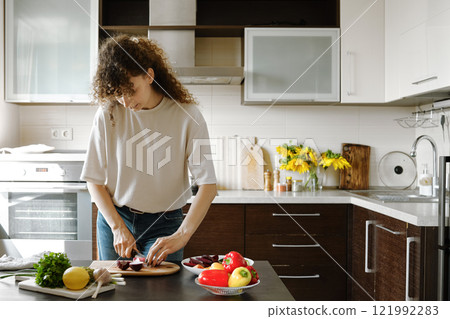 Woman cutting an onion into quarters while preparing lunch Woman cutting an onion into quarters while preparing lunch 121992283
