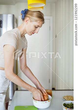 Woman preparing a meal by mixing ingredients in a bowl in a modern kitchen during the day Woman preparing a meal by mixing ingredients in a bowl in a modern kitchen during the day 121992299