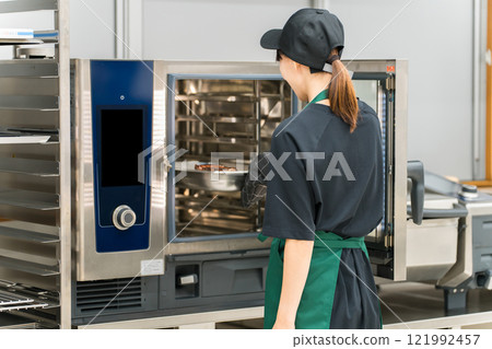A female chef using a steam oven in the kitchen A female chef using a steam oven in the kitchen 121992457