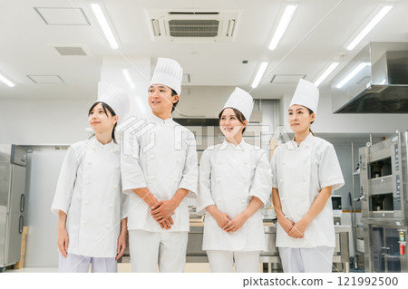 Chefs and cooks in chef coats standing in the kitchen 121992500