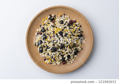 An overhead view of 16-grain rice served on a wooden plate on a white background 121992631