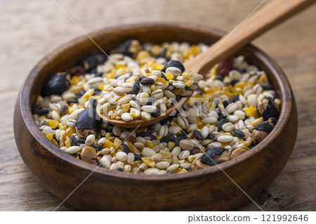 Sixteen grain rice on a plate and a wooden spoon on a wooden table 121992646