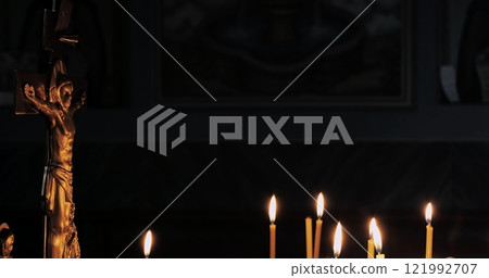 Faithful woman ignites candles in holy church, expressing devotion and connection with god. Traditional orthodox ritual amidst glowing candlelight in a tranquil and spiritual setting. 121992707
