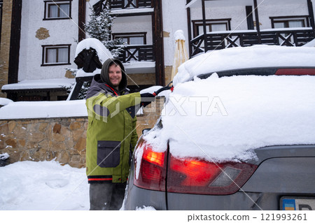 Person Clearing Snow from Car in Winter Landscape Person Clearing Snow from Car in Winter Landscape 121993261