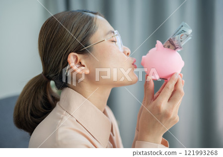 Asian woman try to kissing a piggy bank, she loved to save money. A piggy bank is a small container used to save coins, often but not always shaped like a pig. Asian woman try to kissing a piggy bank, she loved to save money. A piggy bank is a small container used to save coins, often but not always shaped like a pig. 121993268