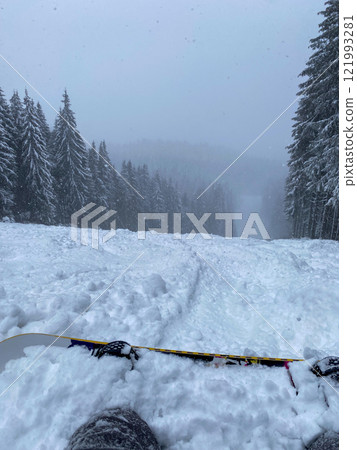 Snowy Ski Slope with Snowboard in Foreground 121993281