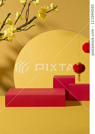 Close-up view of vacant red rectangular podiums used for product displays; crimson lanterns and yellow apricot flowers adorn in a yellow backdrop. Ideal for the Lunar New Year theme. Close-up view of vacant red rectangular podiums used for product displays; crimson lanterns and yellow apricot flowers adorn in a yellow backdrop. Ideal for the Lunar New Year theme. 121994080