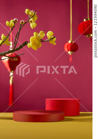 Concept for the Lunar New Year. Frontal view of a crimson background and an empty red cylindrical pedestal for displaying product. Decorated with Chinese lanterns in red and yellow apricot blooms.  121994090