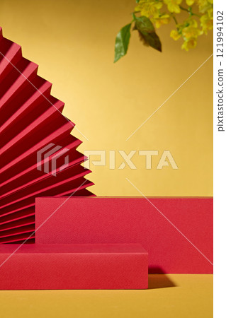A front perspective of two platforms with a space for displaying products. Accompanied by yellow apricots and a big red paper fan for decor. An ideal for Chinese New Year, with a golden background. 121994102