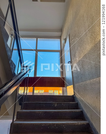 well-lit concrete staircase with a handrail and a window overlooking a clear sky. High quality photo 121994168