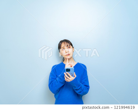 A woman thinking while watching a smartphone A woman thinking while watching a smartphone 121994619