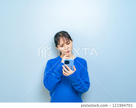 A woman troubled while watching a smartphone 121994701
