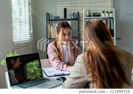 Businesswoman sitting at desk on couch in workplace or at home working on laptop and analyzing data on charts and graphs and writing on papers to make business plan and strategies for company 121994728
