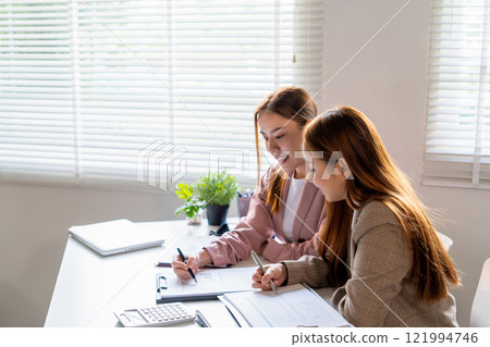 Businesswoman sitting at desk on couch in workplace or at home working on laptop and analyzing data on charts and graphs and writing on papers to make business plan and strategies for company Businesswoman sitting at desk on couch in workplace or at home working on laptop and analyzing data on charts and graphs and writing on papers to make business plan and strategies for company 121994746