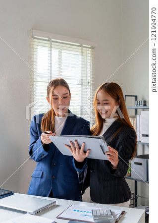 Businesswoman sitting at desk on couch in workplace or at home working on laptop and analyzing data on charts and graphs and writing on papers to make business plan and strategies for company Businesswoman sitting at desk on couch in workplace or at home working on laptop and analyzing data on charts and graphs and writing on papers to make business plan and strategies for company 121994770