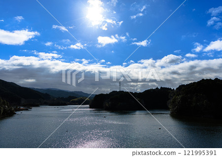 The extremely cold Nara Nunome Dam. From the leaden sky to the spring sun. The low sun shining on the cold lake surface. 121995391