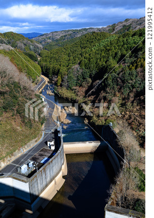 The Nunome Dam in Nara in the extreme cold. From the leaden sky to the spring, the Nunome River flows down in the sunlight. The Nunome Dam in Nara in the extreme cold. From the leaden sky to the spring, the Nunome River flows down in the sunlight. 121995412