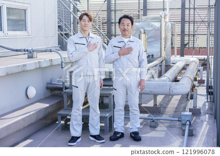 兩名穿著工作服的男子站在屋頂給排水設備前攝影合作：電波學園教育法人東京電子學校。 121996078