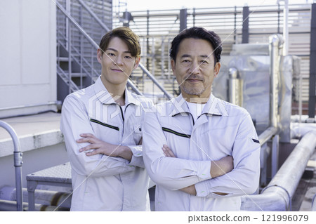 兩名穿著工作服的男子站在屋頂給排水設備前攝影合作：電波學園教育法人東京電子學校。 121996079