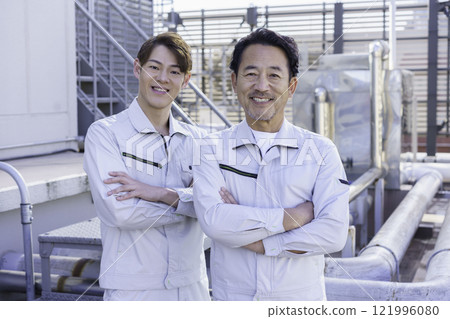 Two men in work clothes standing in front of the water supply and drainage equipment on the roof. Photo courtesy of Tokyo Electronics College, Denpa Gakuen Corporation. Two men in work clothes standing in front of the water supply and drainage equipment on the roof. Photo courtesy of Tokyo Electronics College, Denpa Gakuen Corporation. 121996080