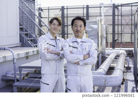 兩名穿著工作服的男子站在屋頂給排水設備前攝影合作：電波學園教育法人東京電子學校。 121996081