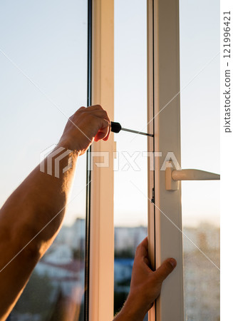Hand of worker adjusting plastic window. 121996421