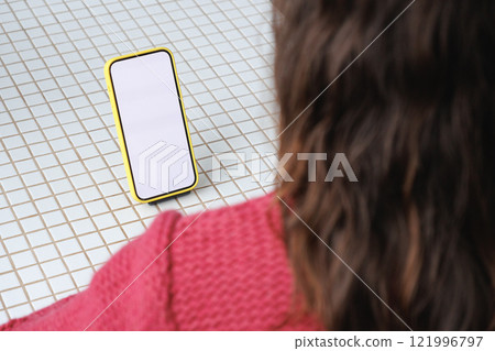 close-up image of woman in pink sitting indoors and using her smartphone. mock-up 121996797