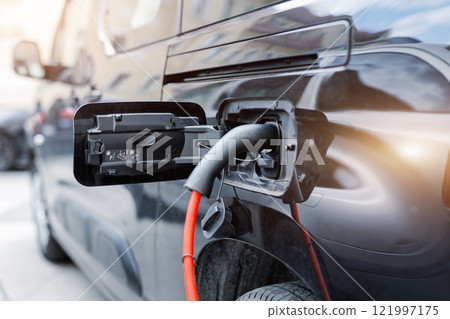 Close-up modern electric plug-in hybrid car van parked near fast charger charging station point center street old European city. Eco friendly green energy vehicle. Zero emission transport technology 121997175