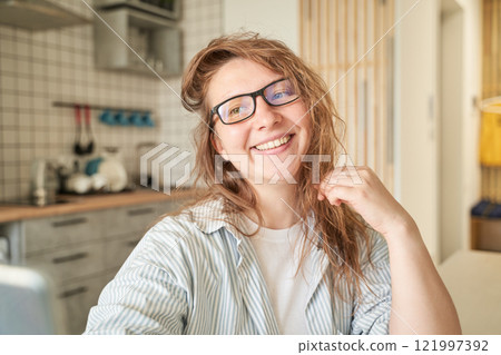 Smiling caucasian young female with glasses in cozy modern kitchen interior 121997392