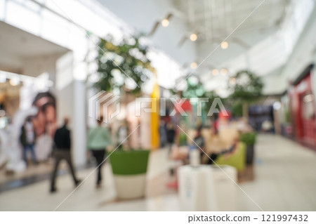 Blurred view of shoppers in a modern mall interior with natural lighting 121997432
