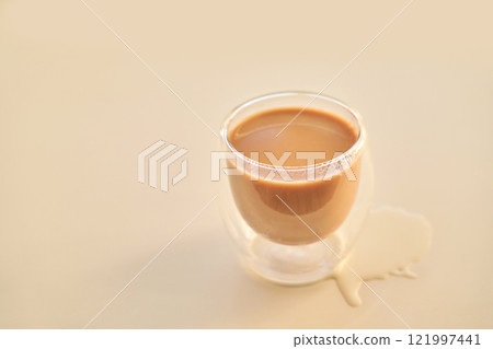 Double walled glass cup with spilled coffee on light beige surface Double walled glass cup with spilled coffee on light beige surface 121997441