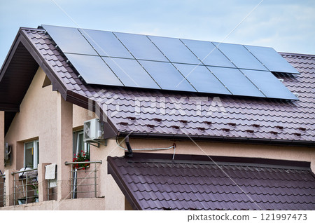 House with solar panels on rooftop for generating electricity through photovoltaic effect. Home with solar power system on roof. Concept of alternative energy, autonomy, power sustainable resources. 121997473