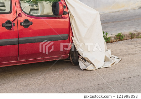 Red minivan after car accident with frontal impact is parked near sidewalk in street, covered with awning so not to spoil city landscape. Consequences of collision, costs, damage, insurance indemnity Red minivan after car accident with frontal impact is parked near sidewalk in street, covered with awning so not to spoil city landscape. Consequences of collision, costs, damage, insurance indemnity 121998858