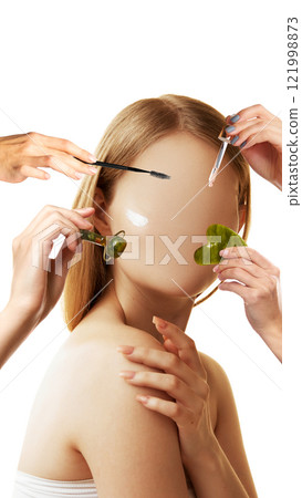 Conceptual art design. Model with glowing skin, hands applying skincare tools like roller, serum, and scrubber symbolizing self-care and beauty rituals Conceptual art design. Model with glowing skin, hands applying skincare tools like roller, serum, and scrubber symbolizing self-care and beauty rituals 121998873