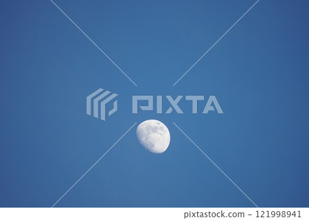 月亮漂浮在萬裡無雲的藍天上 121998941