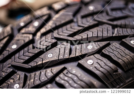 close-up of snow tire with metal studs, which improve traction on icy surfaces, studded winter tyre 121999032