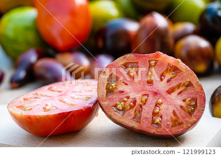 table with a cutting board with sliced tomatoes and different colored tomatoes in the background 121999123