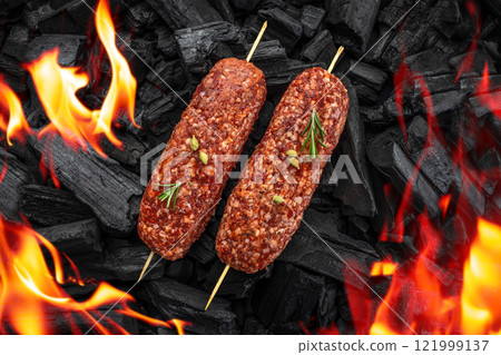 kebab of lamb, Lula kebab on skewers with spices on BBQ grill coal with fire flames. top view Beef on grill 121999137