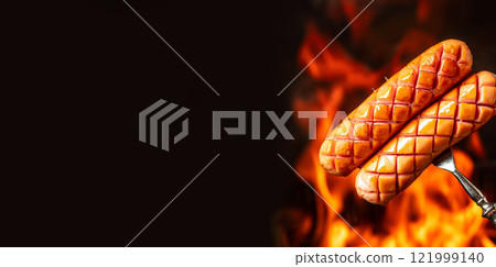juicy sausages grilled on fire with smoke on a fork, copy space for text 121999140