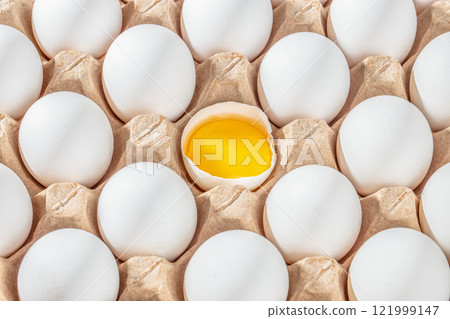 Row of white eggs and single broken egg with a yolk. White Eggs and Yellow Egg Yolk. Individuality and difference concept Row of white eggs and single broken egg with a yolk. White Eggs and Yellow Egg Yolk. Individuality and difference concept 121999147