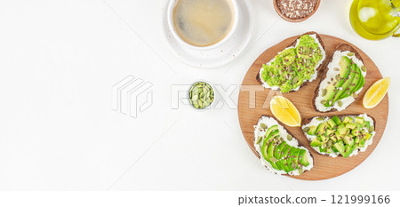 Avocado toasts bread with avocado and a cup of coffee. Vegan breakfast menu on a white background top view. copy space Avocado toasts bread with avocado and a cup of coffee. Vegan breakfast menu on a white background top view. copy space 121999166