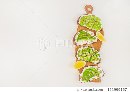Set of Avocado toasts Sandwiches with avocado and cream cheese with grain bread on a wooden board on a white background top view. copy space 121999167