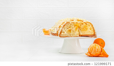 Traditional Italian cake Panettone with tangerine cream. Large panettone with a slice cut on a white background, copy space 121999171