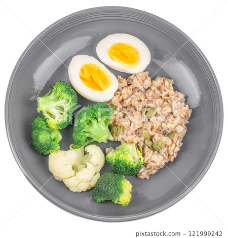 Breakfast oatmeal porridge with boiled egg and broccoli isolated on white background. top view. Healthy balanced food Breakfast oatmeal porridge with boiled egg and broccoli isolated on white background. top view. Healthy balanced food 121999242