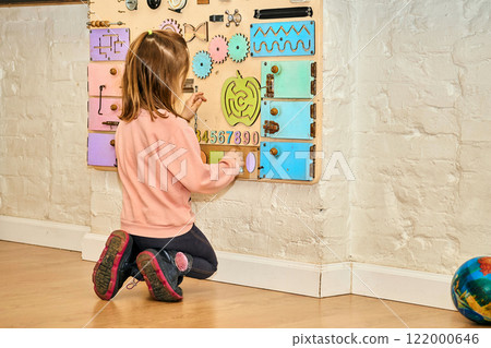 Cute child in kindergarten makes up different shapes on the wall board 122000646