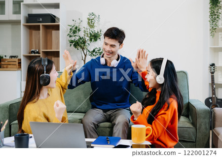 Asian college student reading a book study on laptop prepare for the exam or work on a group project at home. 122001274