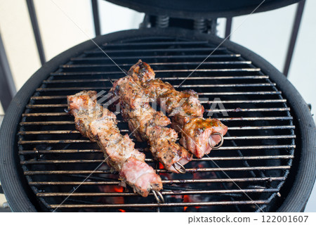 A kamado egg type barbeque grill standing on a living house terrace with a smoke coming from it's chimney, used as a cold smoke house A kamado egg type barbeque grill standing on a living house terrace with a smoke coming from it's chimney, used as a cold smoke house 122001607